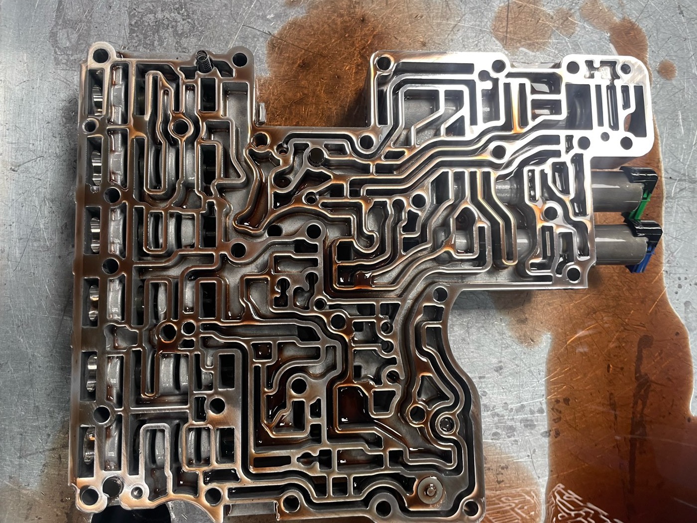 A Ford 10R80 valve body face up on the bench, its hydraulic circuit machined across the casting