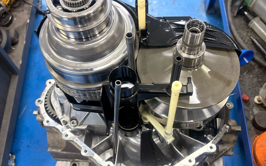 A CVT opened on the bench with both pulleys and the steel belt exposed