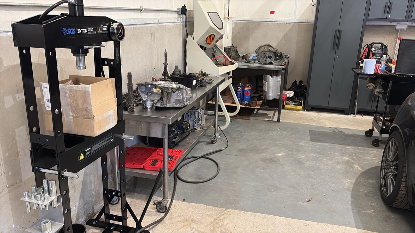 The workshop, with the twenty-tonne press on the left, a transmission case in pieces on the bench, and the parts washer beyond it